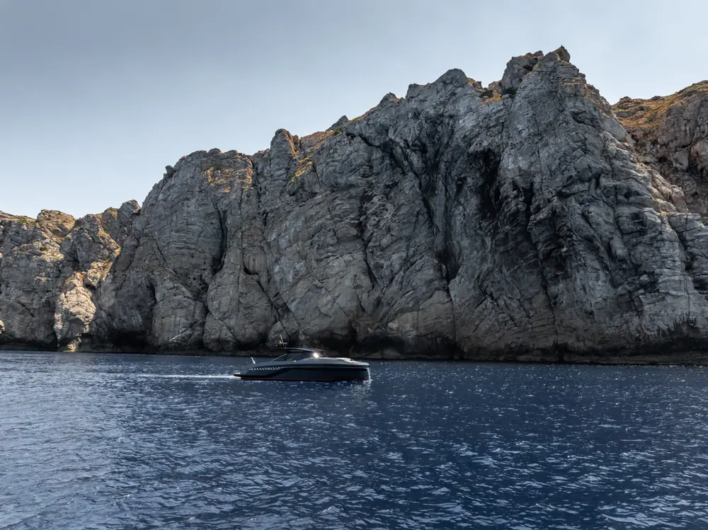 Yacht cruising beneath coastal cliffs
