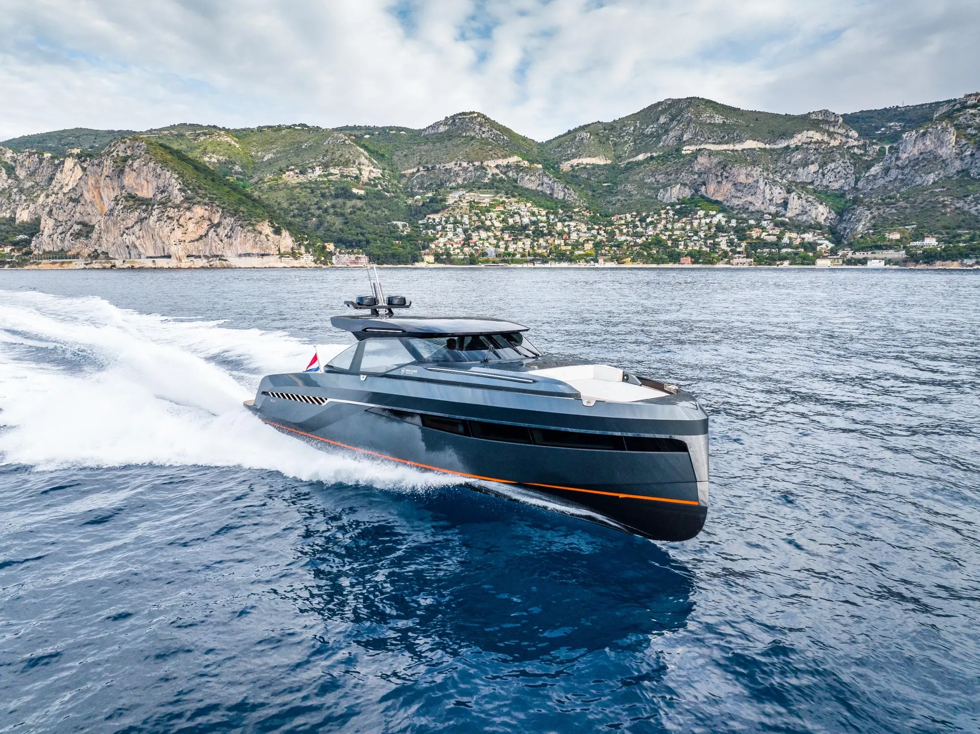 Motor yacht cruising along a mountainous coastline