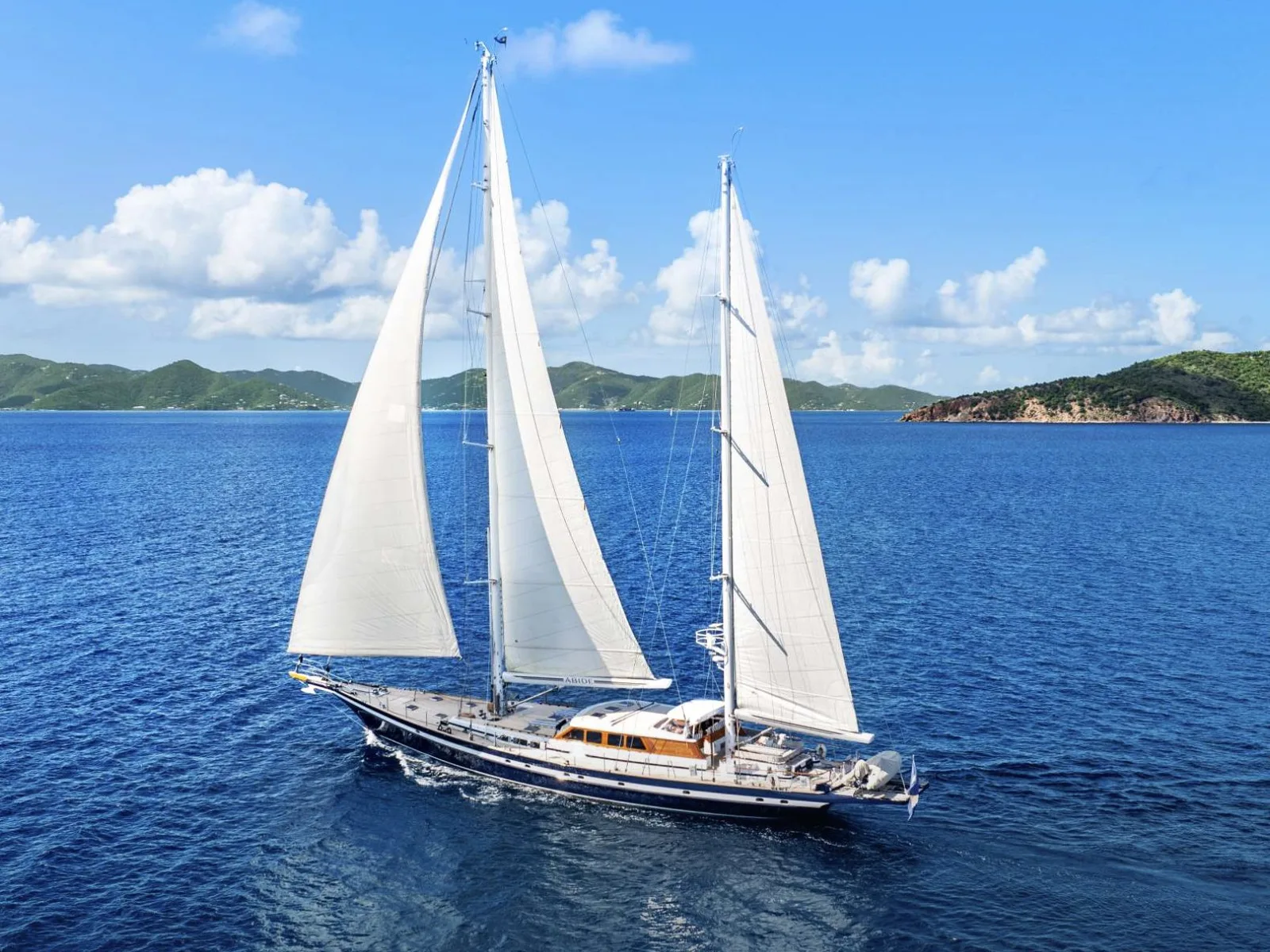 A sailing yacht with full sails on a charter week in a blue bay